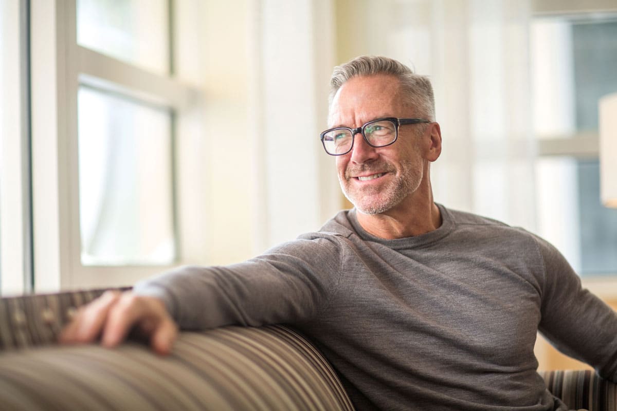 middle-aged man with glasses sitting on couch