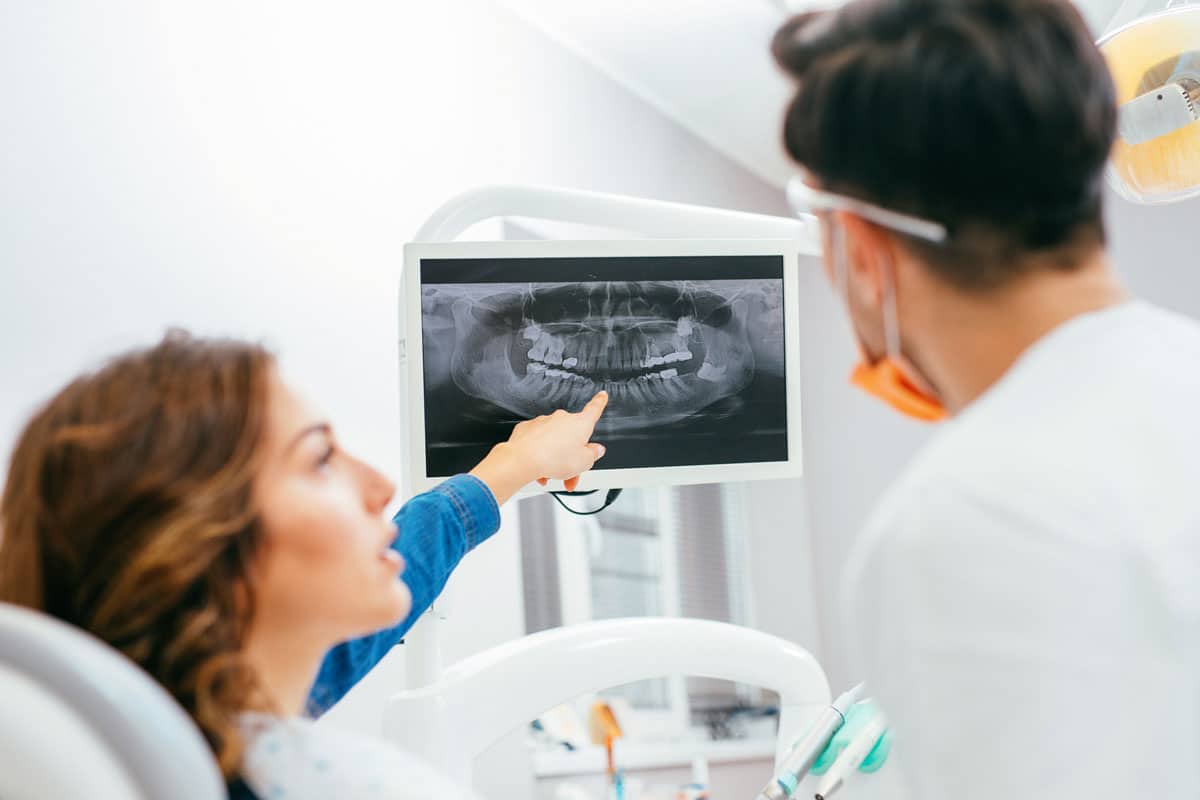 female dental patient pointing to her x-ray