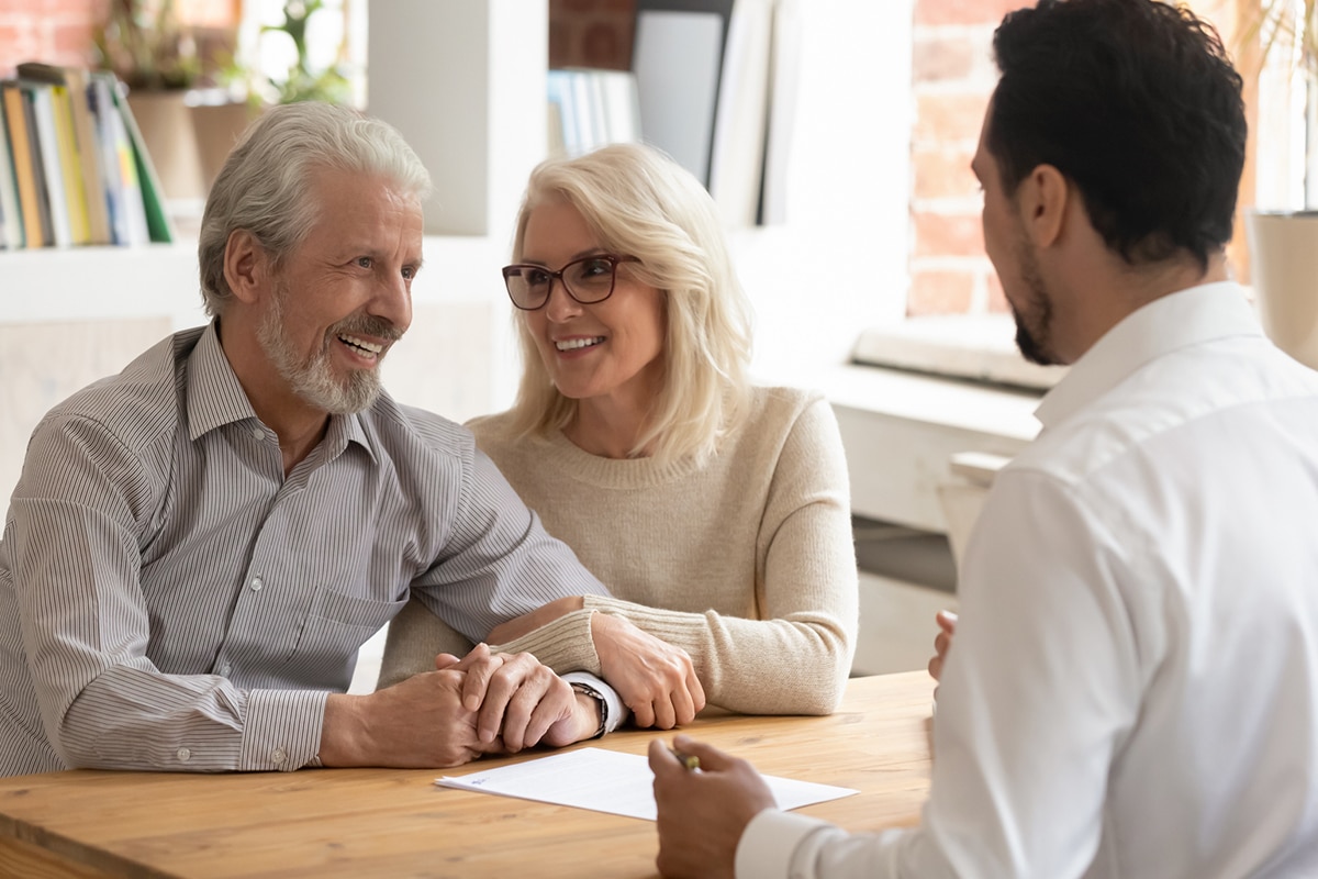 older couple at desk discussing something with a man