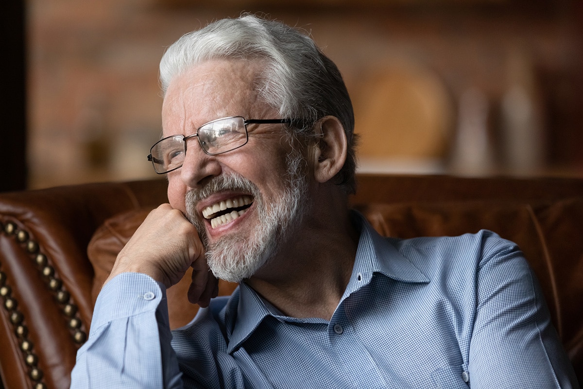smiling older man sitting in brown leather chair