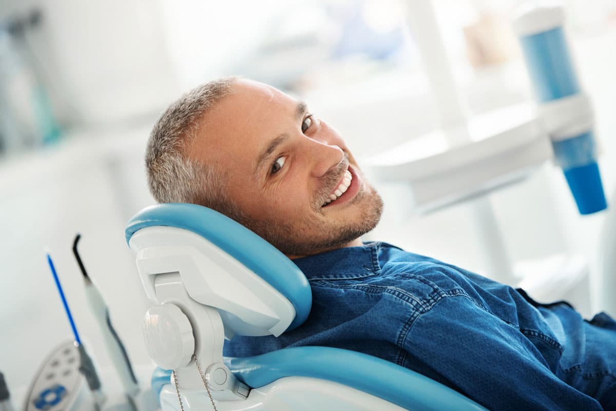 Man sitting in blue and white dental exam chair