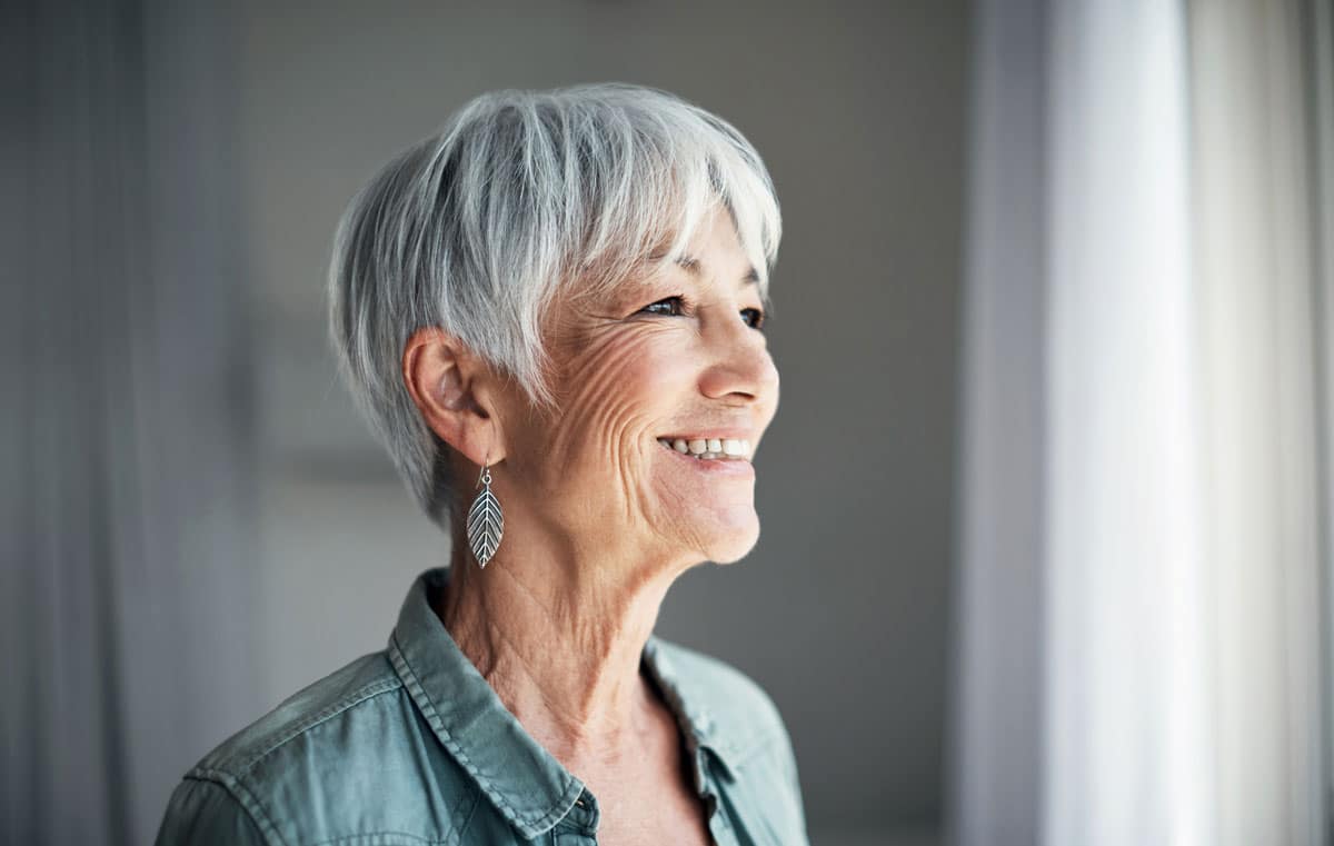 older woman smiling, looking out window