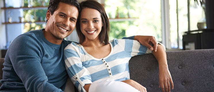 young couple sitting on couch with arms around each other