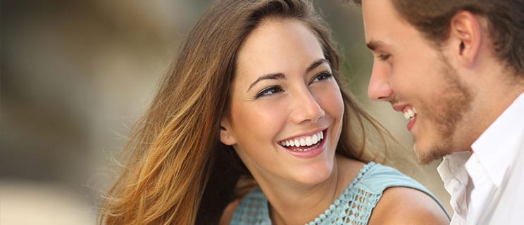 closeup of young girl with long brown hair smiling at man with beard