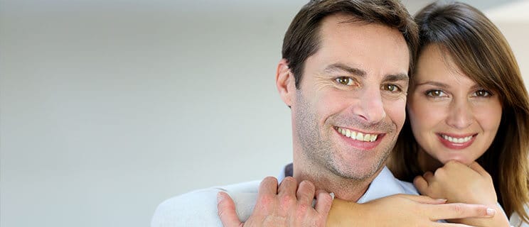 headshot of couple with woman's arm around man's shoulder and neck