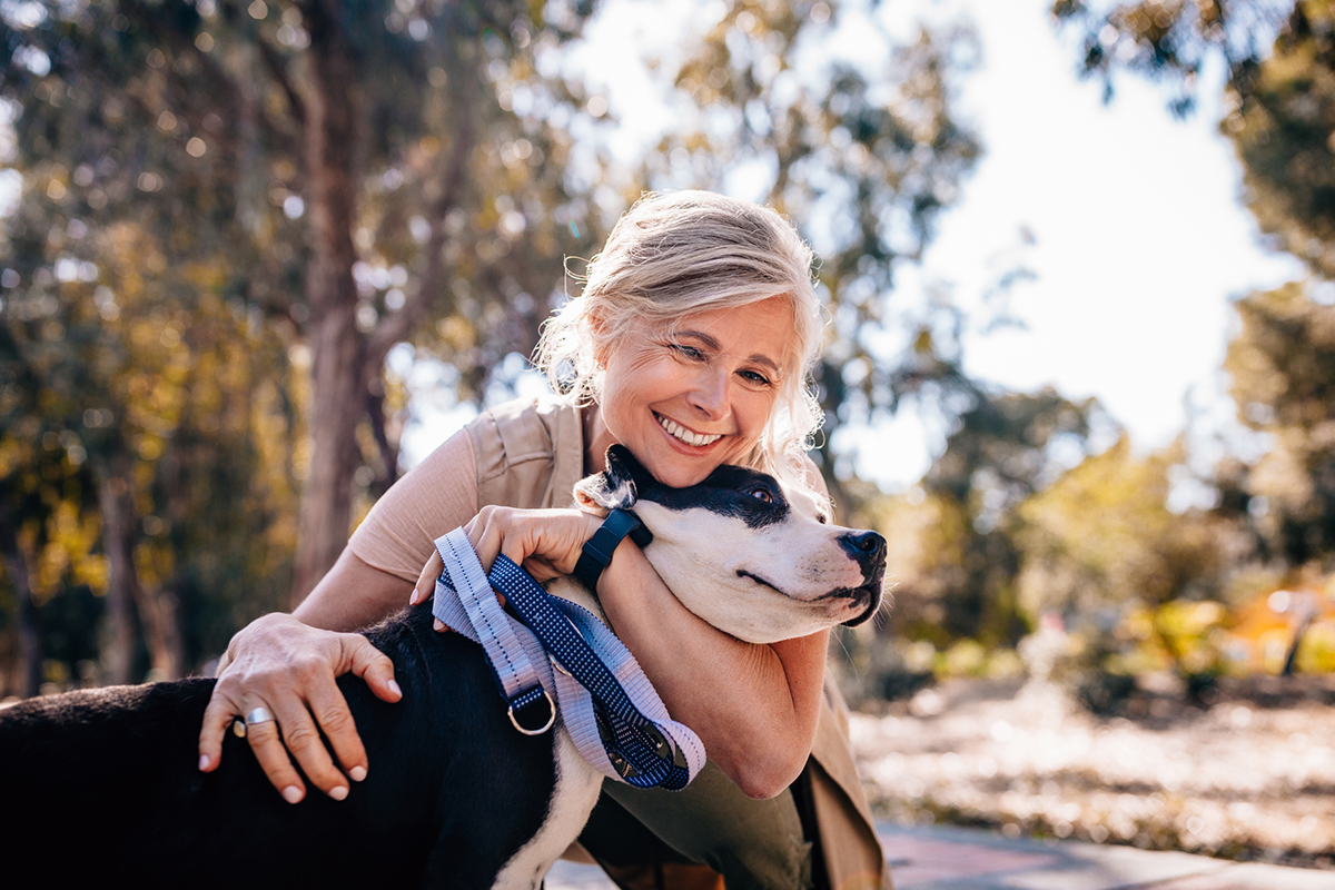 older woman outside, hugging her dog